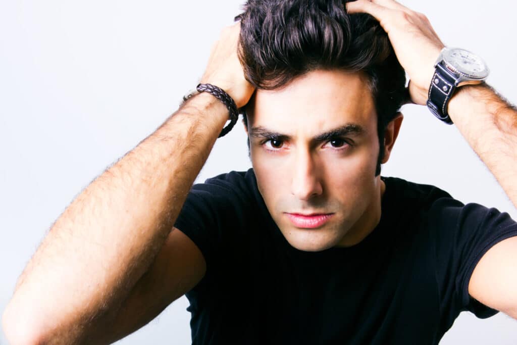 studio portrait of man running fingers through his hair