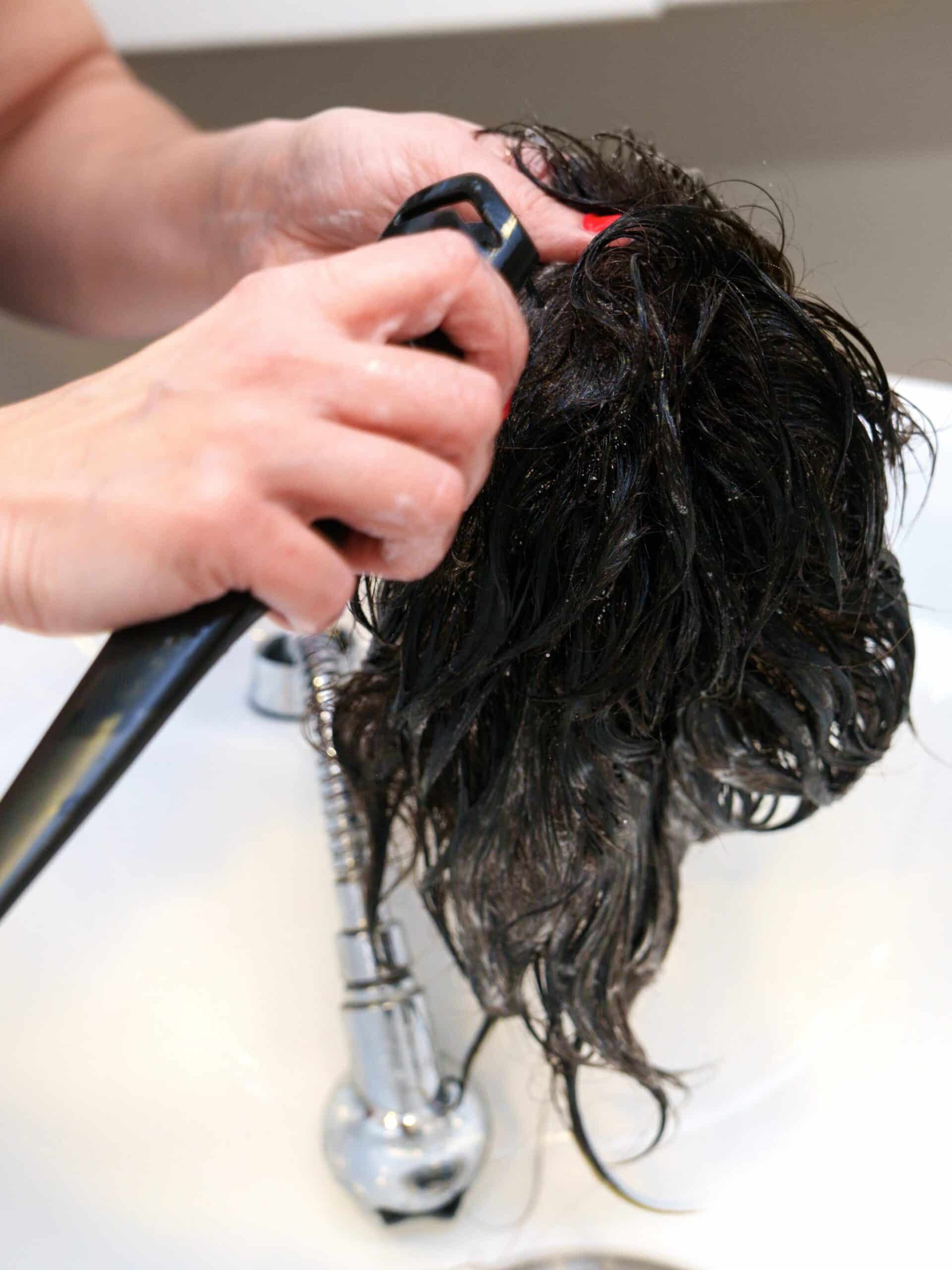 close up of hair system being washed by hair stylist